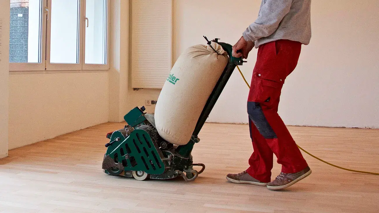Bild Parkettaufbereitung -Ein Servicemann reinigt einen Holzboden mit einem Staubsauger. Raumausstattung Merget | Goethestraße 43 | 63814 Mainaschaff